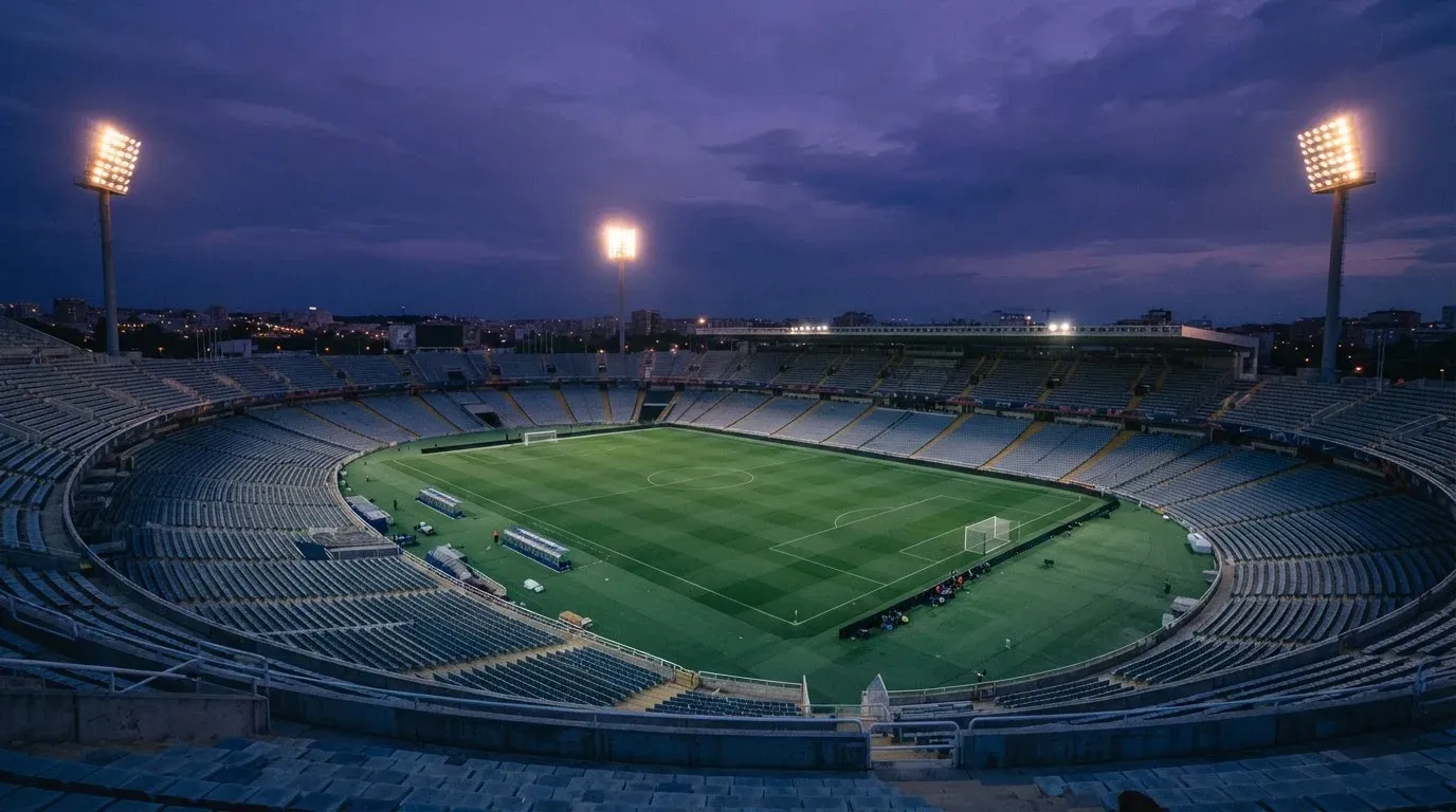 An empty football stadium with floodlight masts at dusk