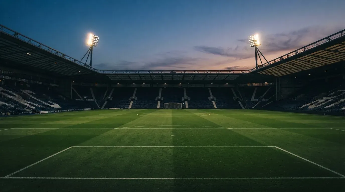 An empty football stadium with floodlight masts at dusk