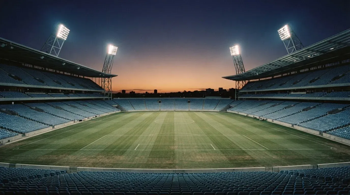An empty football stadium with floodlight masts at dusk
