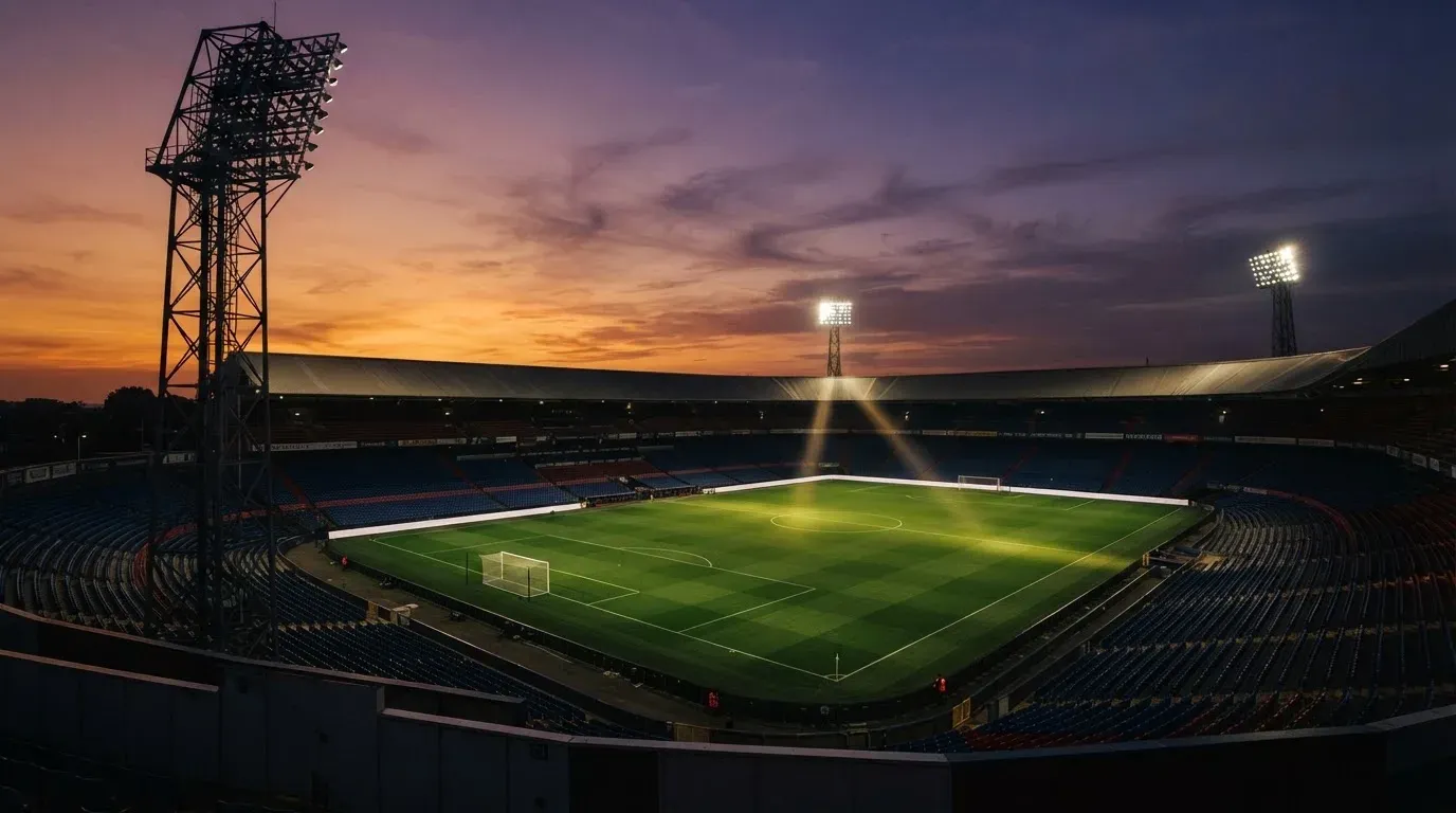 An empty football stadium with floodlight masts at dusk