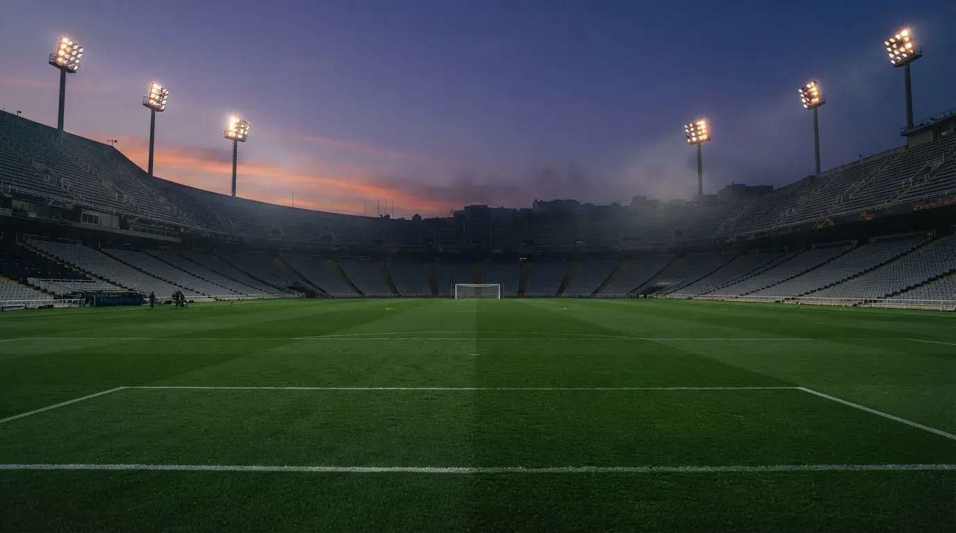 An empty football stadium with floodlight masts at dusk