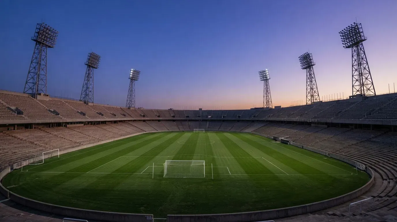 An empty football stadium with floodlight masts at dusk