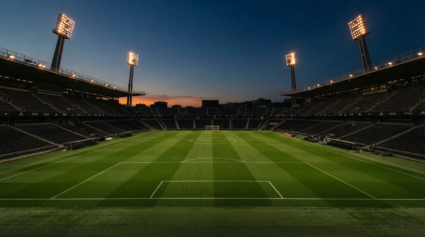 An empty football stadium with floodlight masts at dusk
