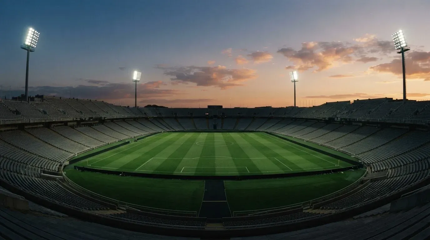An empty football stadium with floodlight masts at dusk