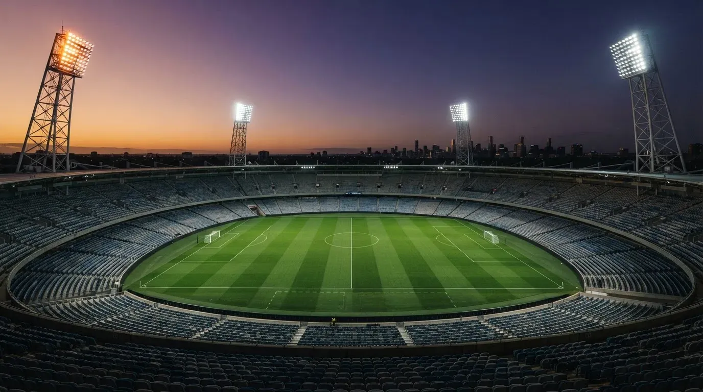 An empty football stadium with floodlight masts at dusk