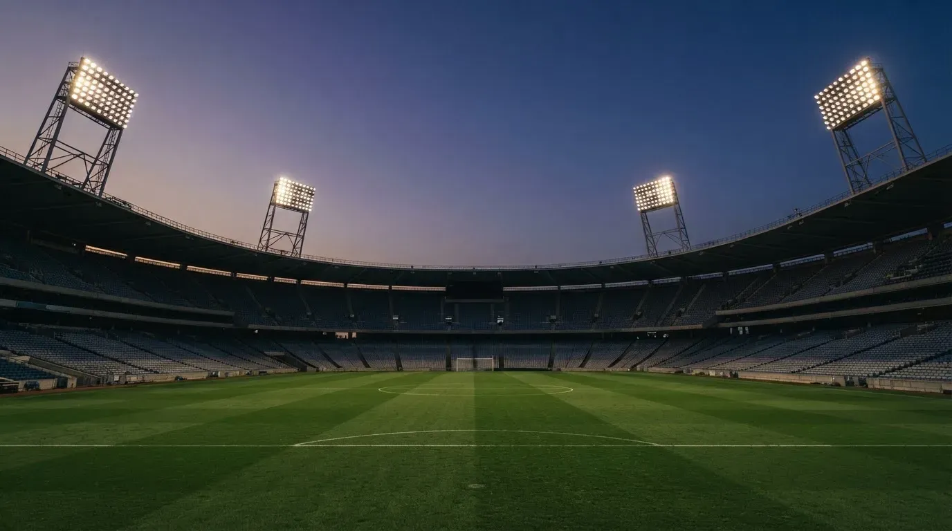 An empty football stadium with floodlight masts at dusk