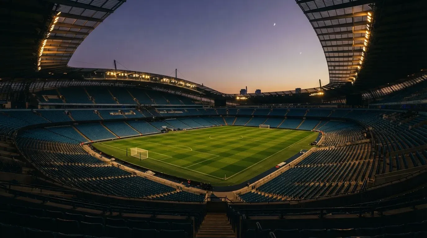 An empty football stadium with floodlight masts at dusk