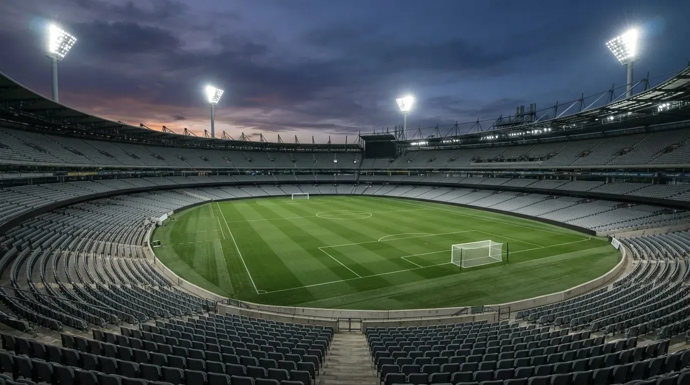 An empty football stadium with floodlight masts at dusk