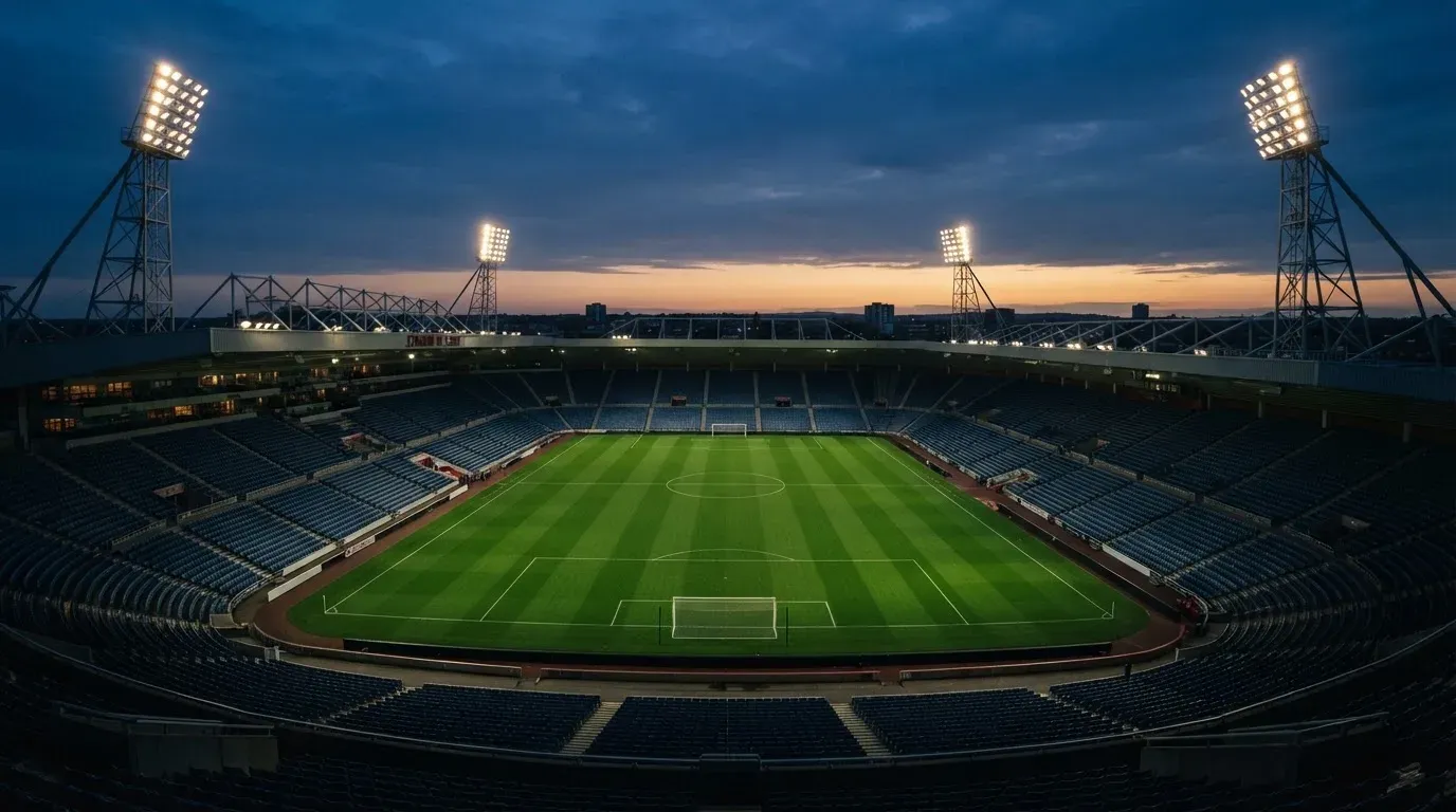 An empty football stadium with floodlight masts at dusk