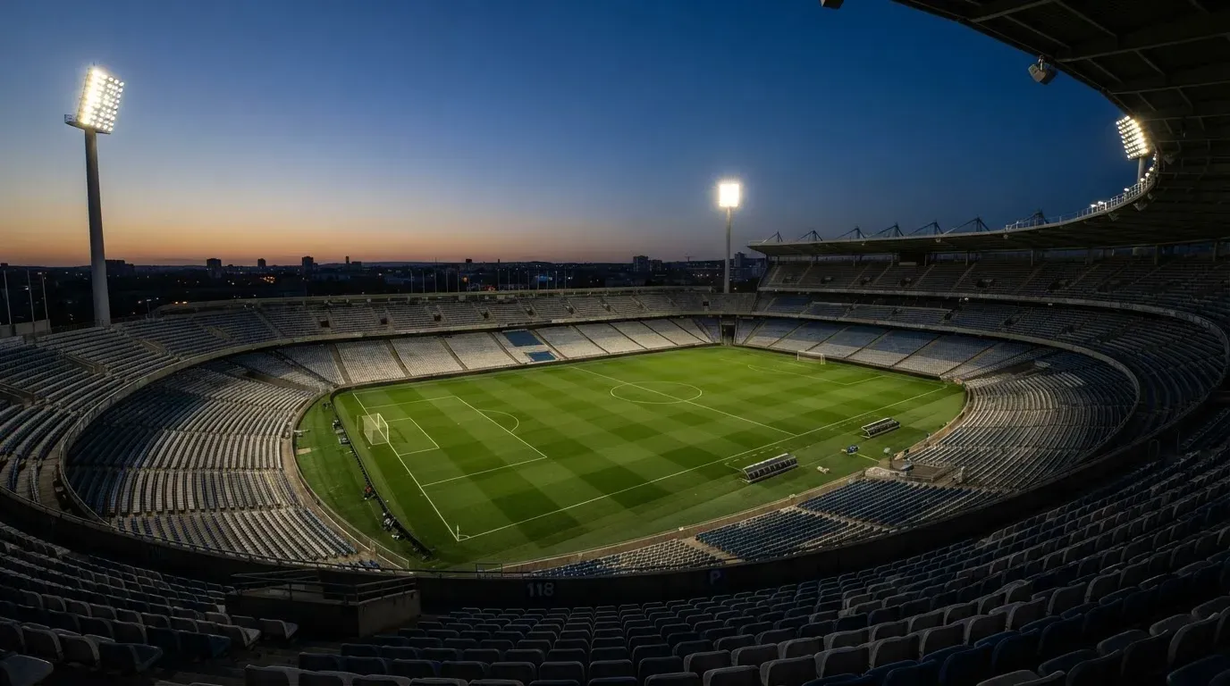 An empty football stadium with floodlight masts at dusk