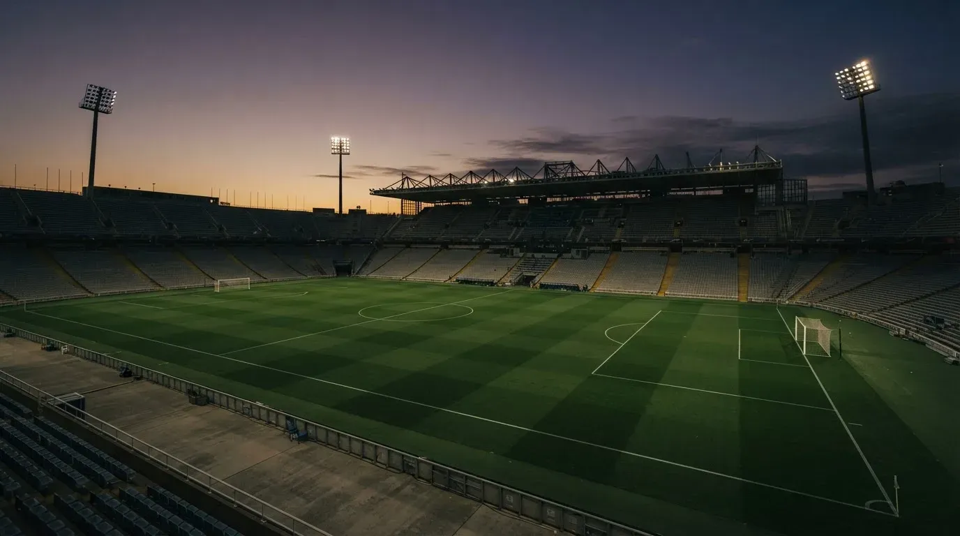 An empty football stadium with floodlight masts at dusk