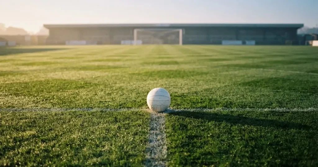 A ball on the centre spot of a grass pitch in morning light