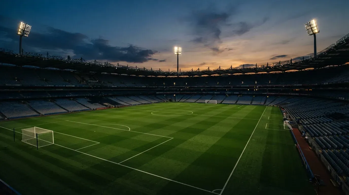 An empty football stadium with floodlight masts at dusk