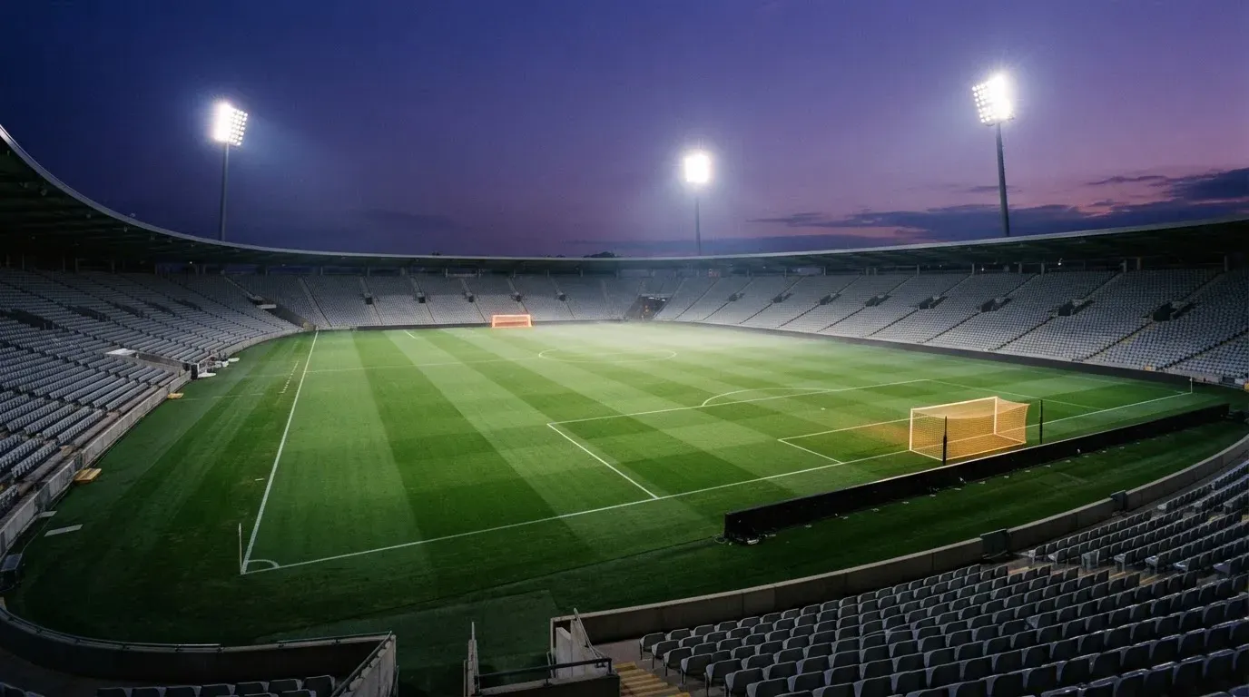 An empty football stadium with floodlight masts at dusk