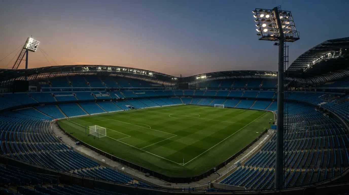 An empty football stadium with floodlight masts at dusk