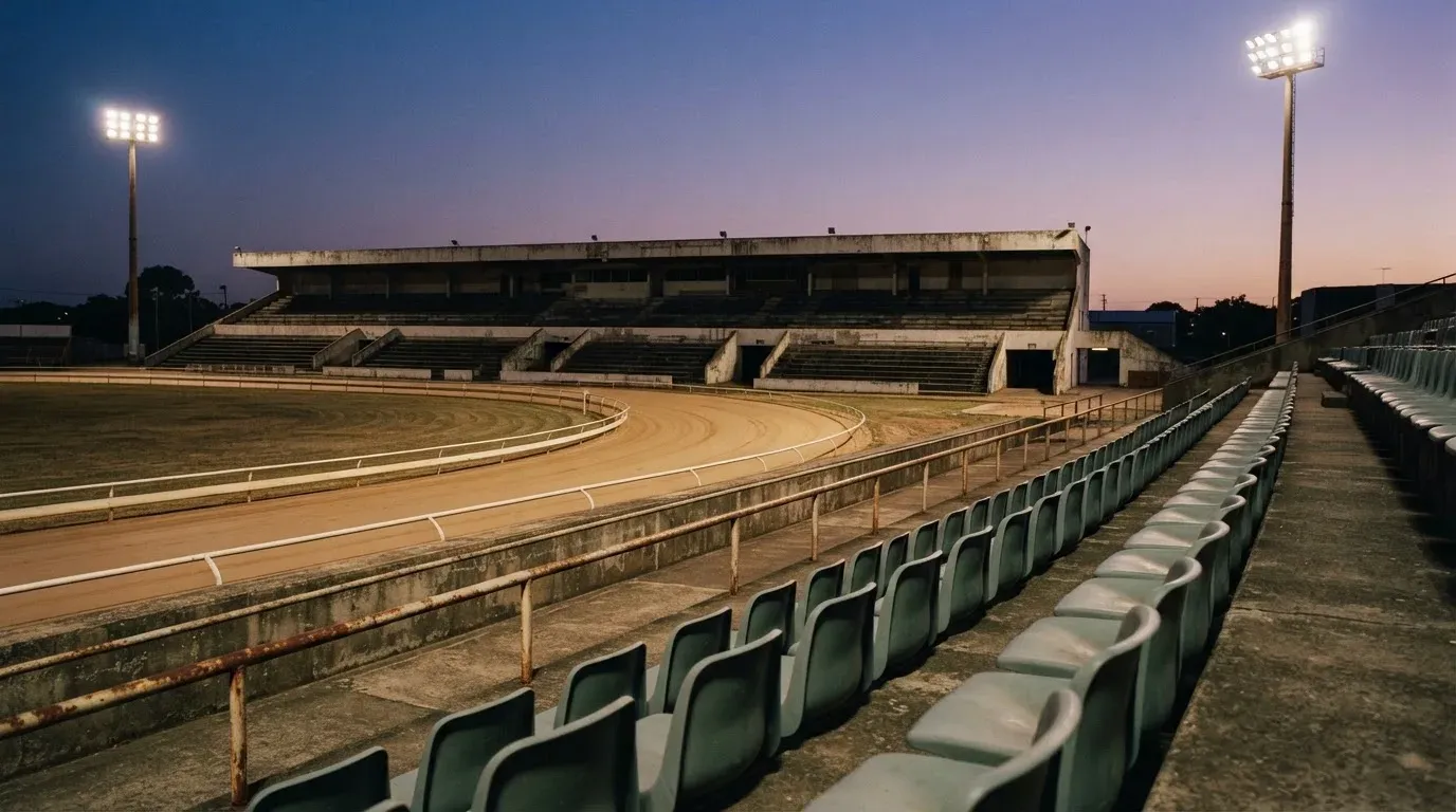 An empty football stadium with floodlight masts at dusk