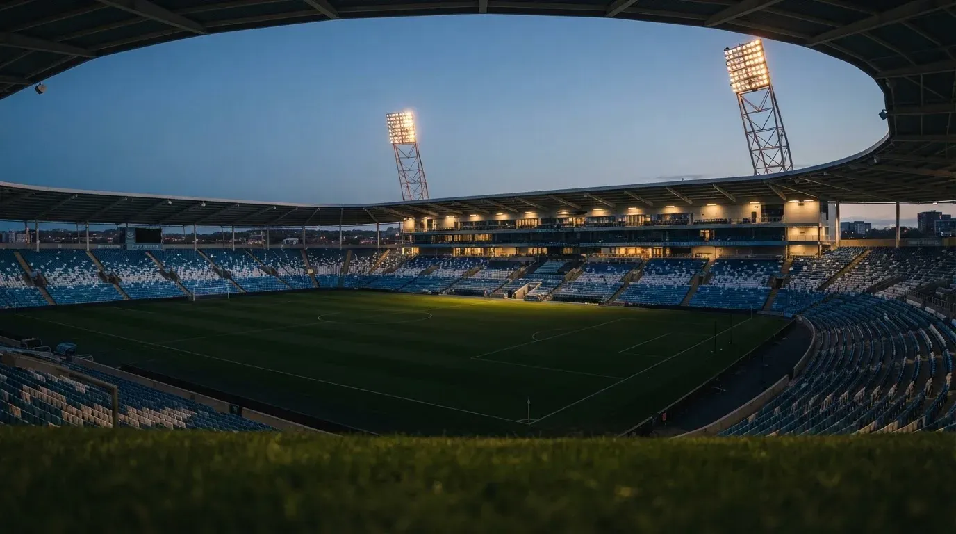 An empty football stadium with floodlight masts at dusk