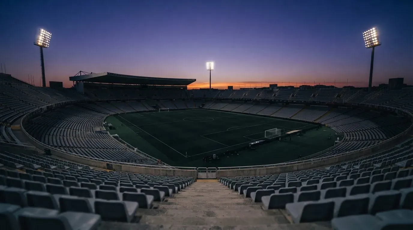 An empty football stadium with floodlight masts at dusk