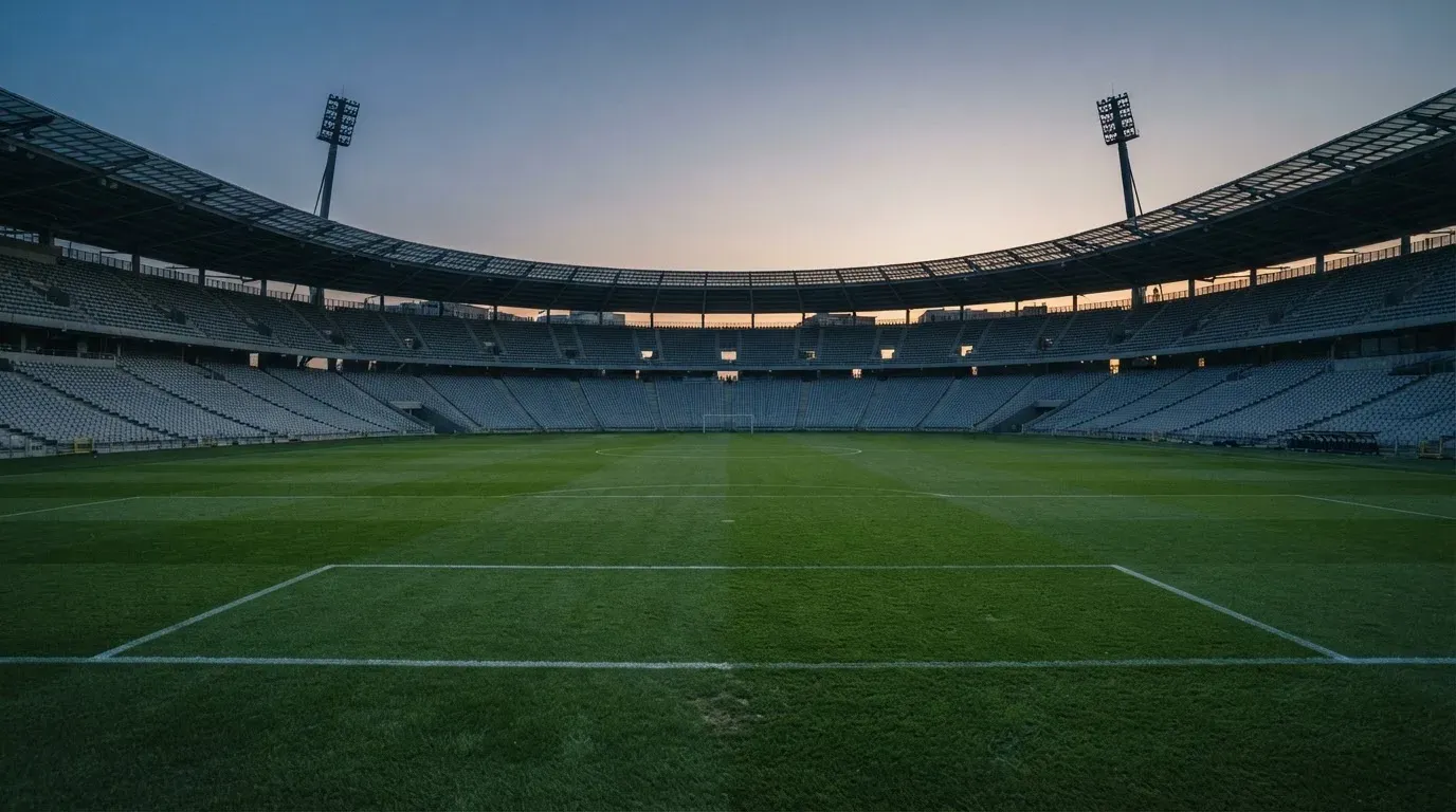 An empty football stadium with floodlight masts at dusk