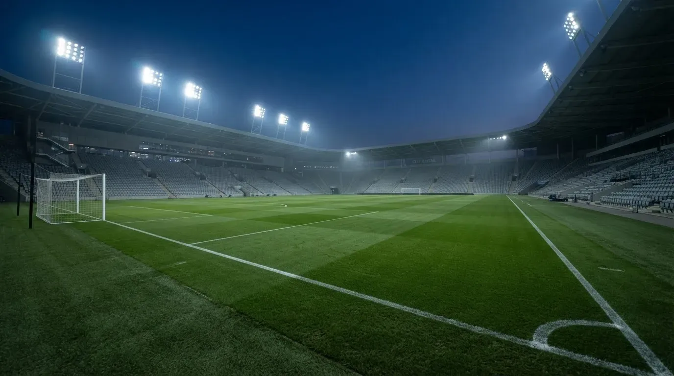 An empty football stadium with floodlight masts at dusk