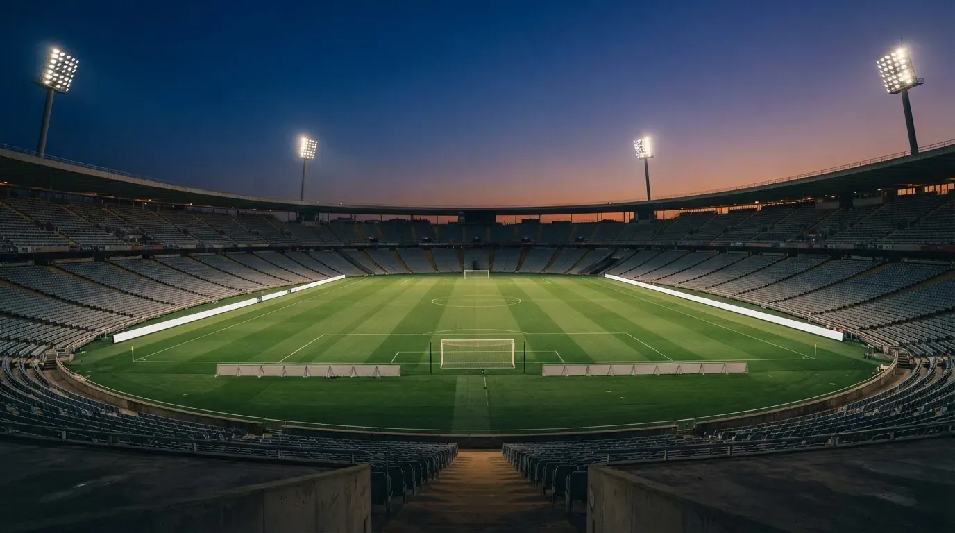 An empty football stadium with floodlight masts at dusk