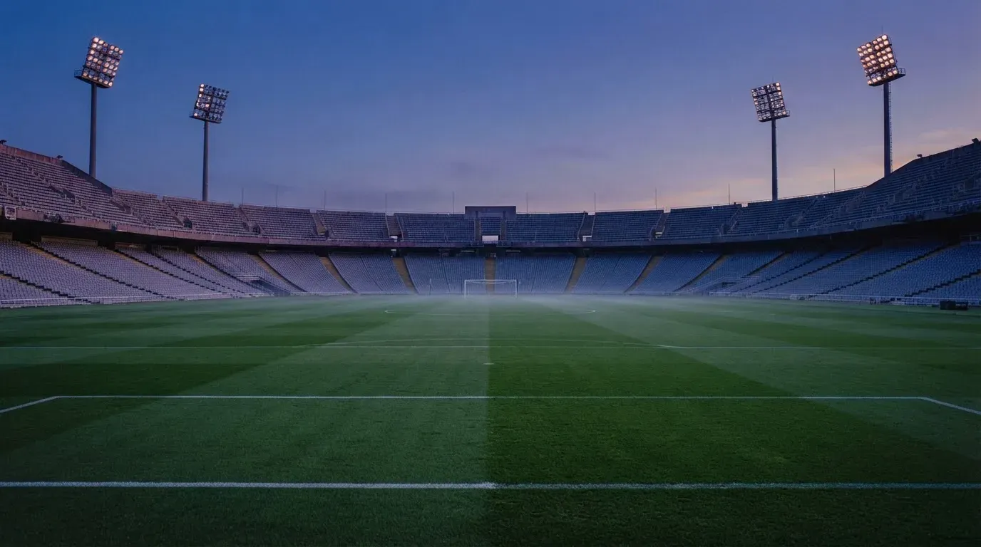 An empty football stadium with floodlight masts at dusk
