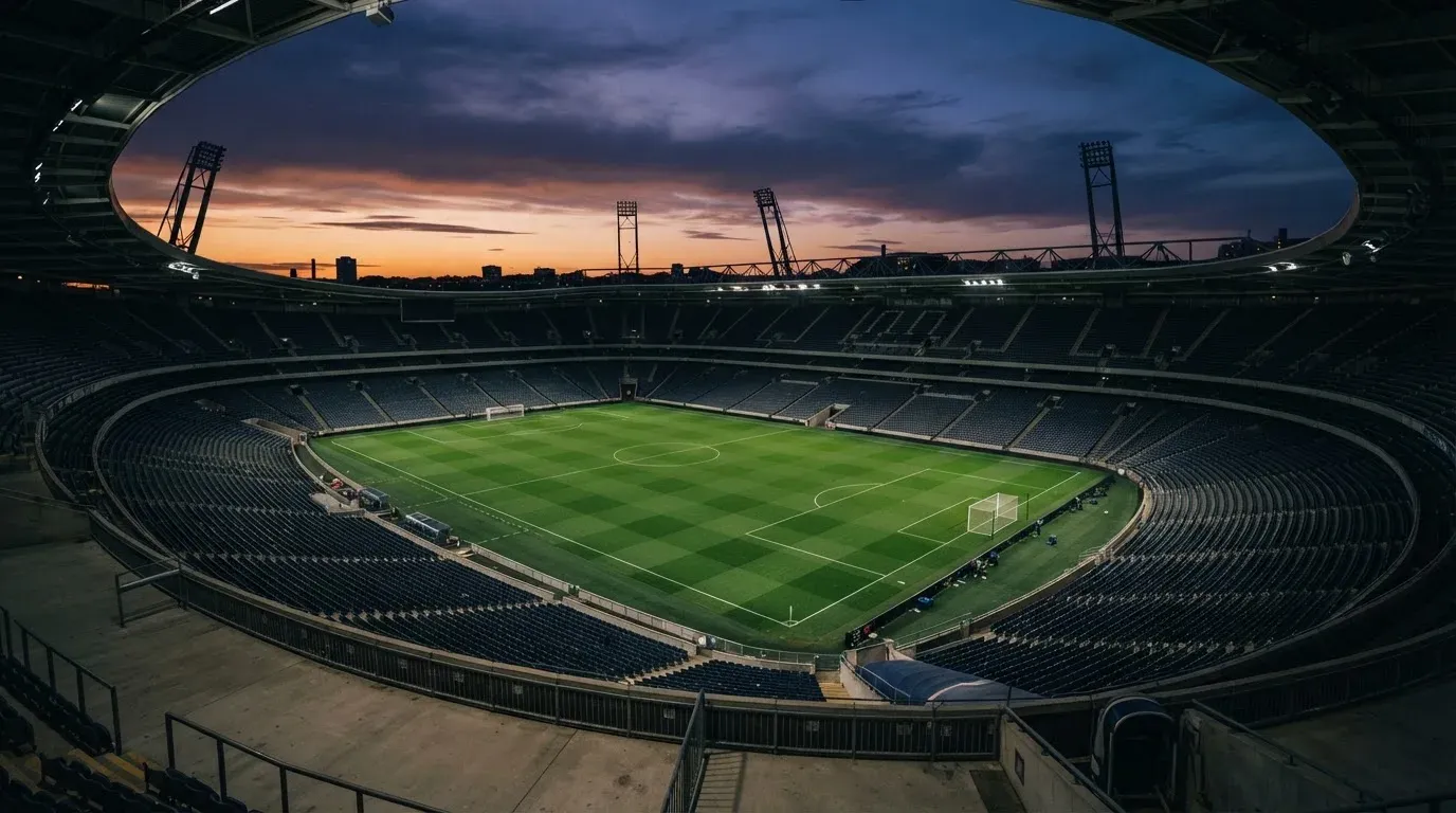 An empty football stadium with floodlight masts at dusk