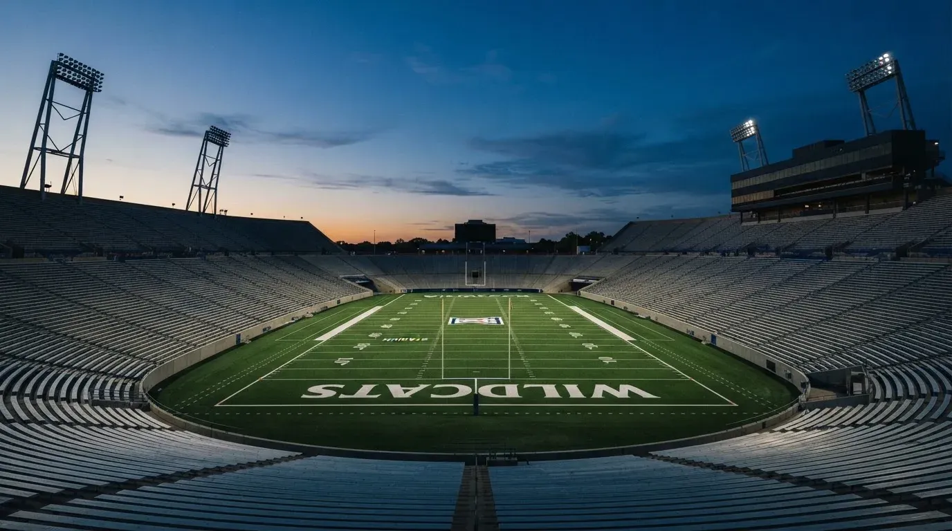 An empty football stadium with floodlight masts at dusk