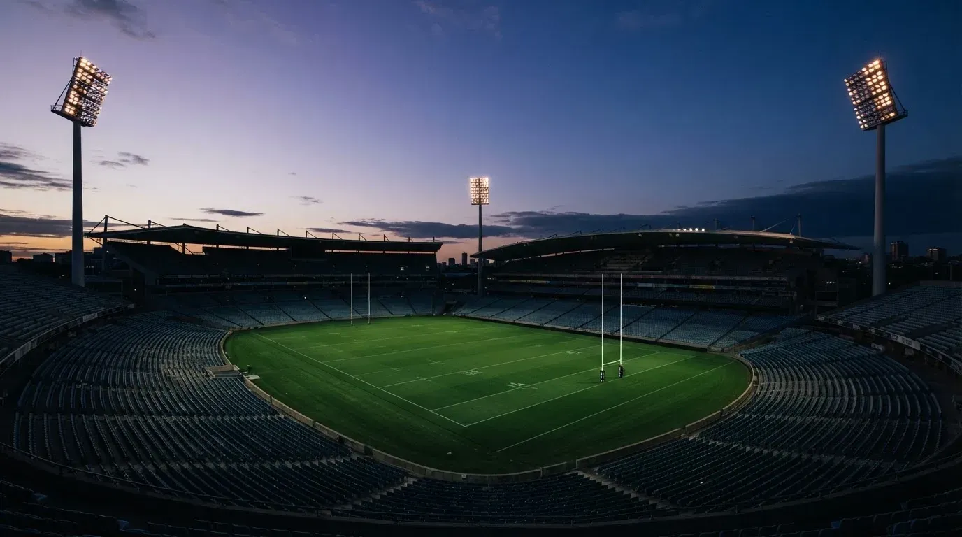 An empty football stadium with floodlight masts at dusk