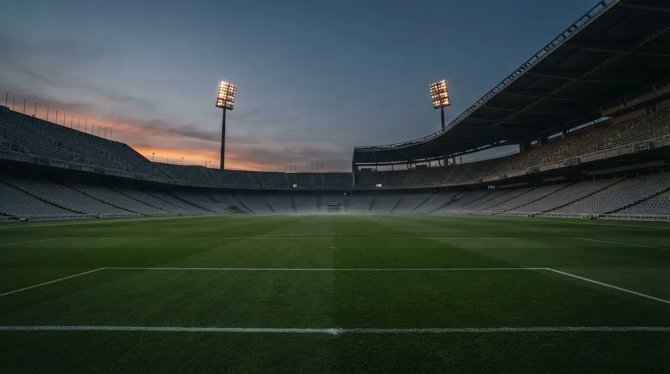 An empty football stadium with floodlight masts at dusk