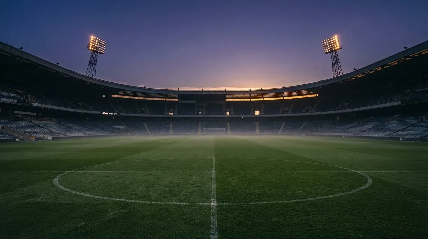 An empty football stadium with floodlight masts at dusk