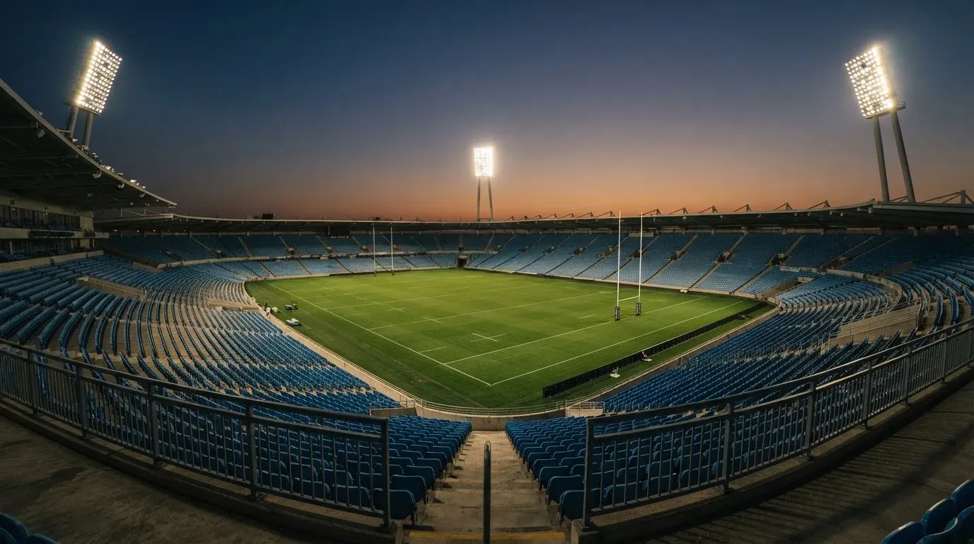 An empty football stadium with floodlight masts at dusk