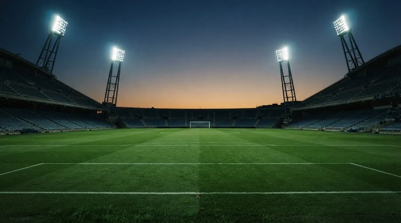 An empty football stadium with floodlight masts at dusk