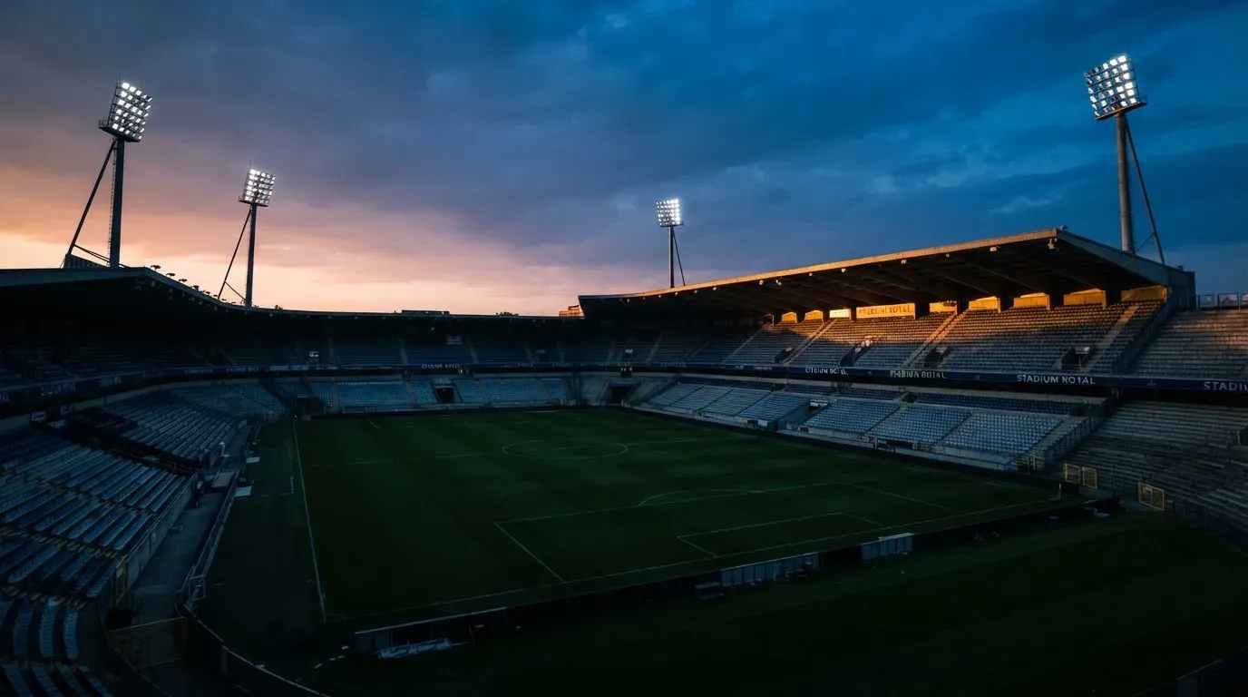 An empty football stadium with floodlight masts at dusk