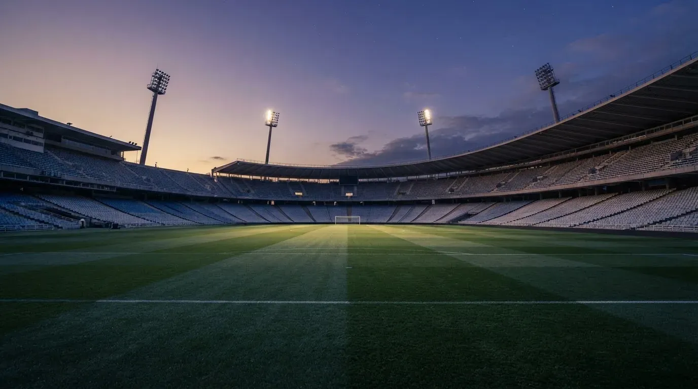 An empty football stadium with floodlight masts at dusk