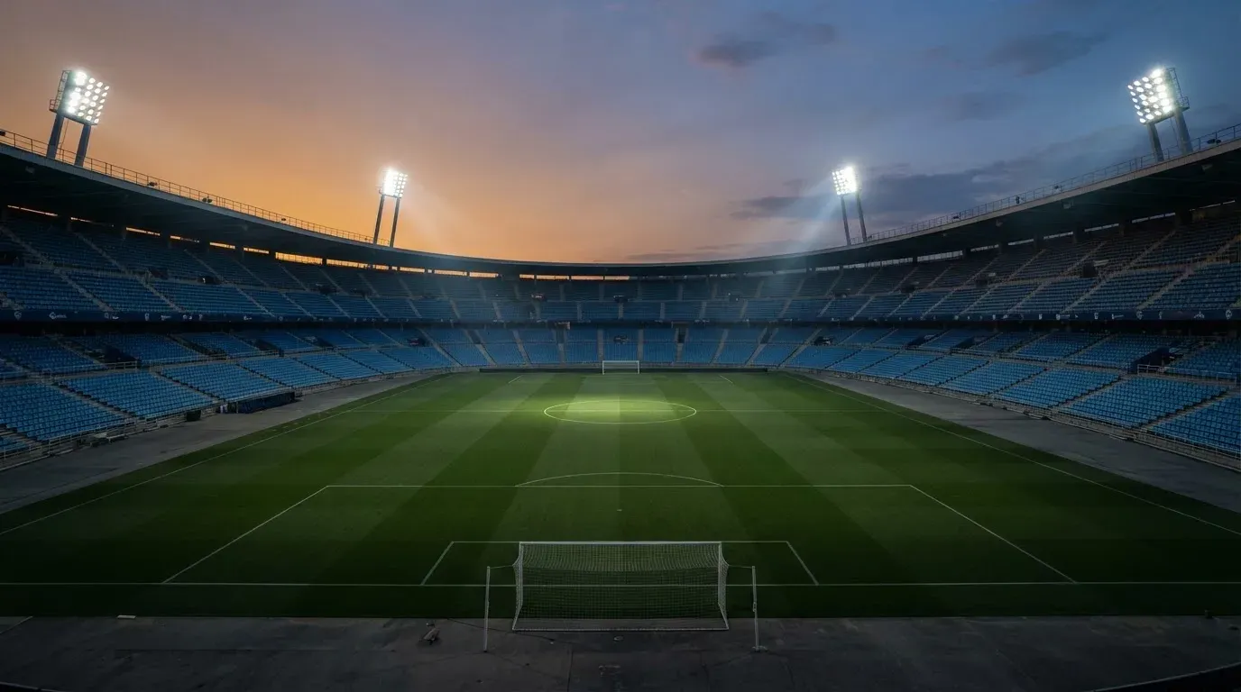 An empty football stadium with floodlight masts at dusk
