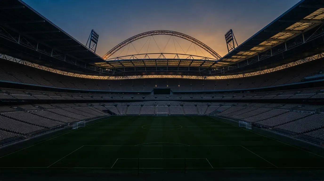 An empty football stadium with floodlight masts at dusk