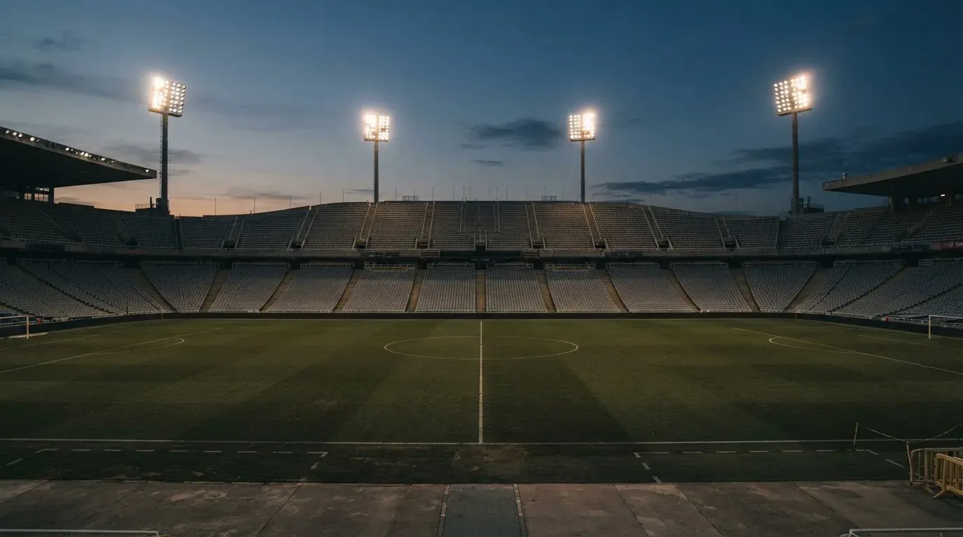An empty football stadium with floodlight masts at dusk