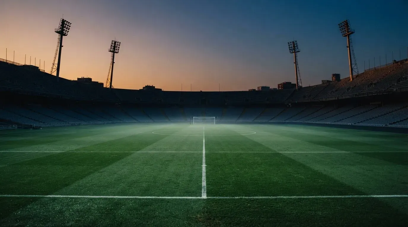 An empty football stadium with floodlight masts at dusk