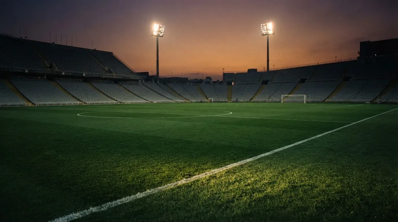 An empty football stadium with floodlight masts at dusk