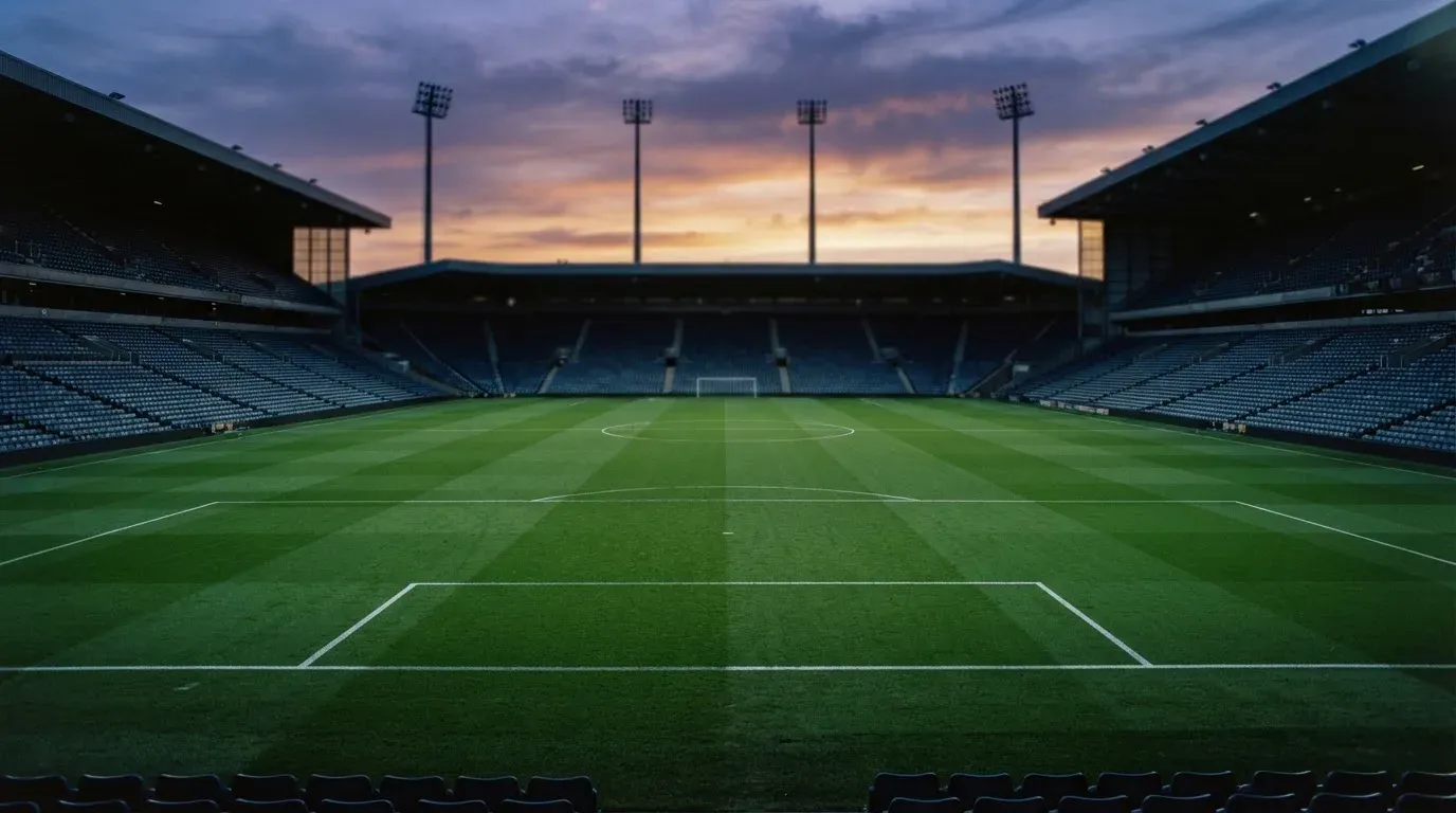 An empty football stadium with floodlight masts at dusk