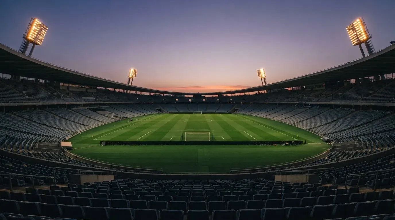 An empty football stadium with floodlight masts at dusk