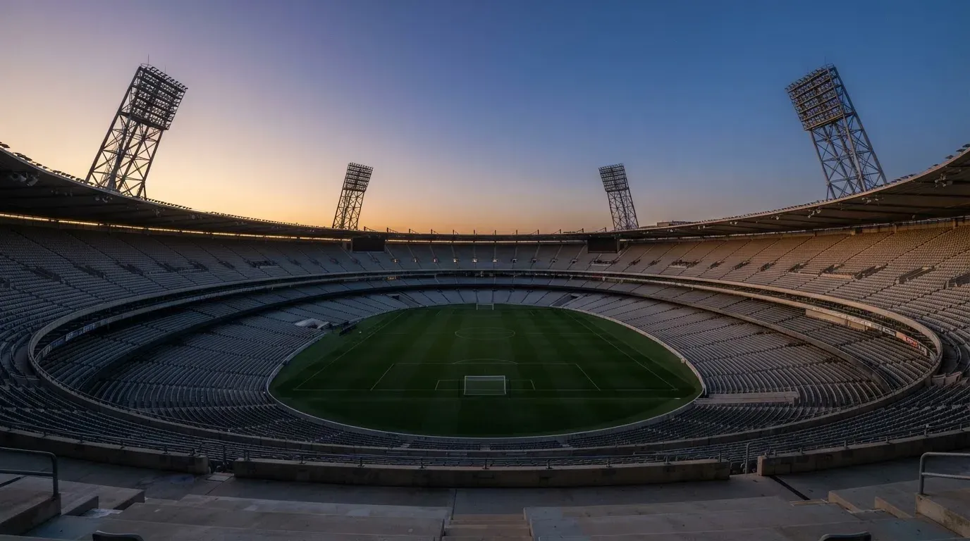 An empty football stadium with floodlight masts at dusk