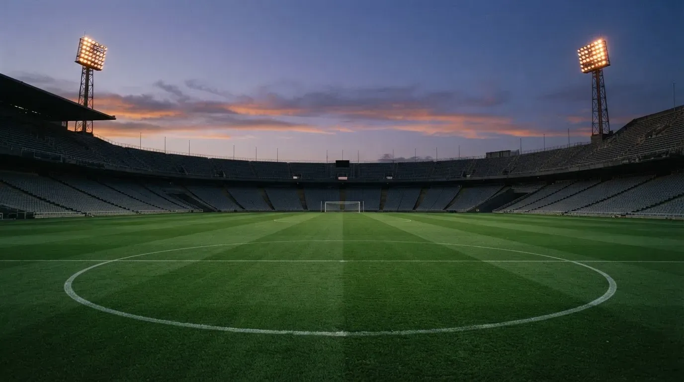 An empty football stadium with floodlight masts at dusk