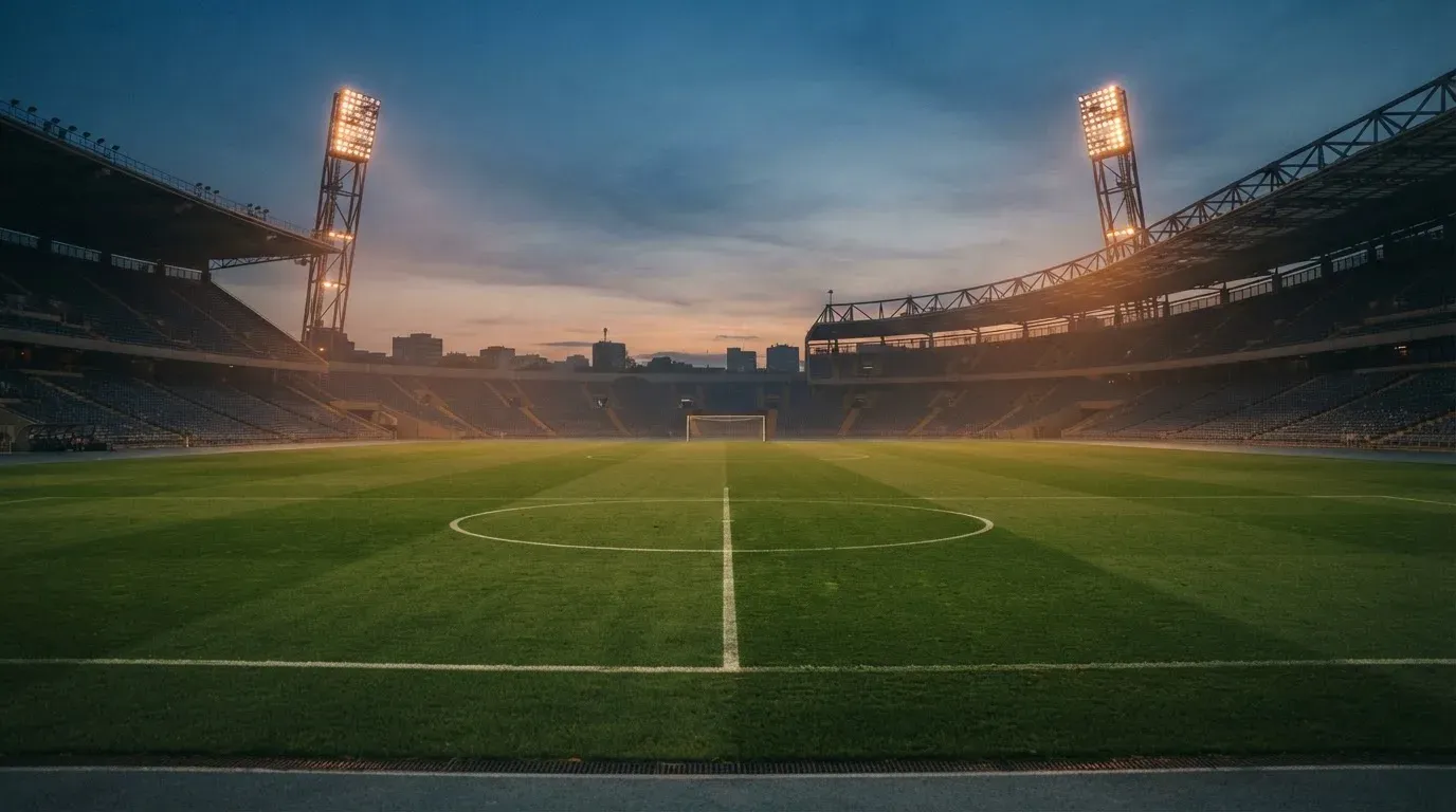 An empty football stadium with floodlight masts at dusk