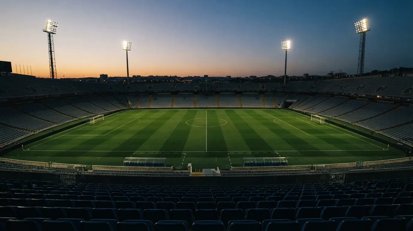 An empty football stadium with floodlight masts at dusk