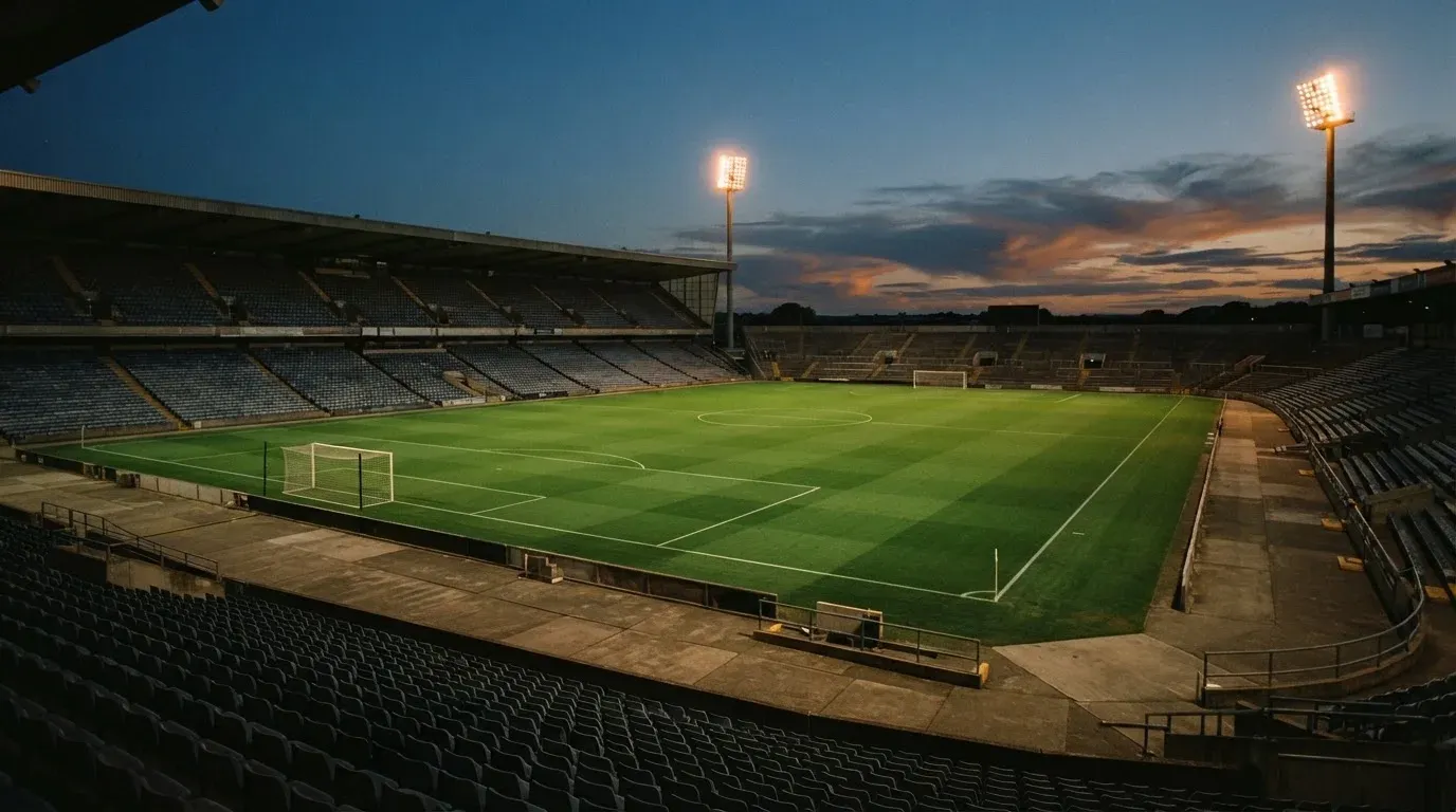 An empty football stadium with floodlight masts at dusk