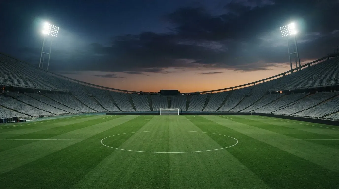 An empty football stadium with floodlight masts at dusk