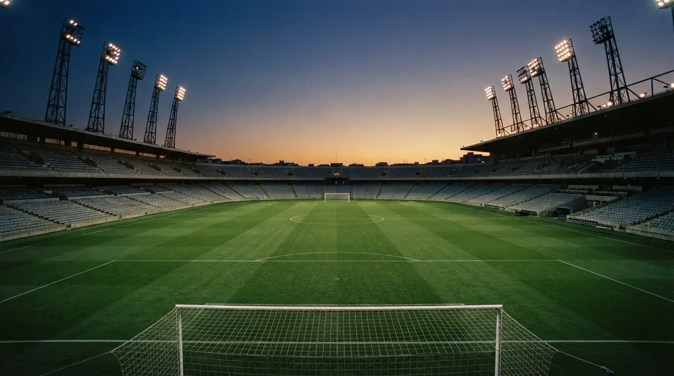 An empty football stadium with floodlight masts at dusk
