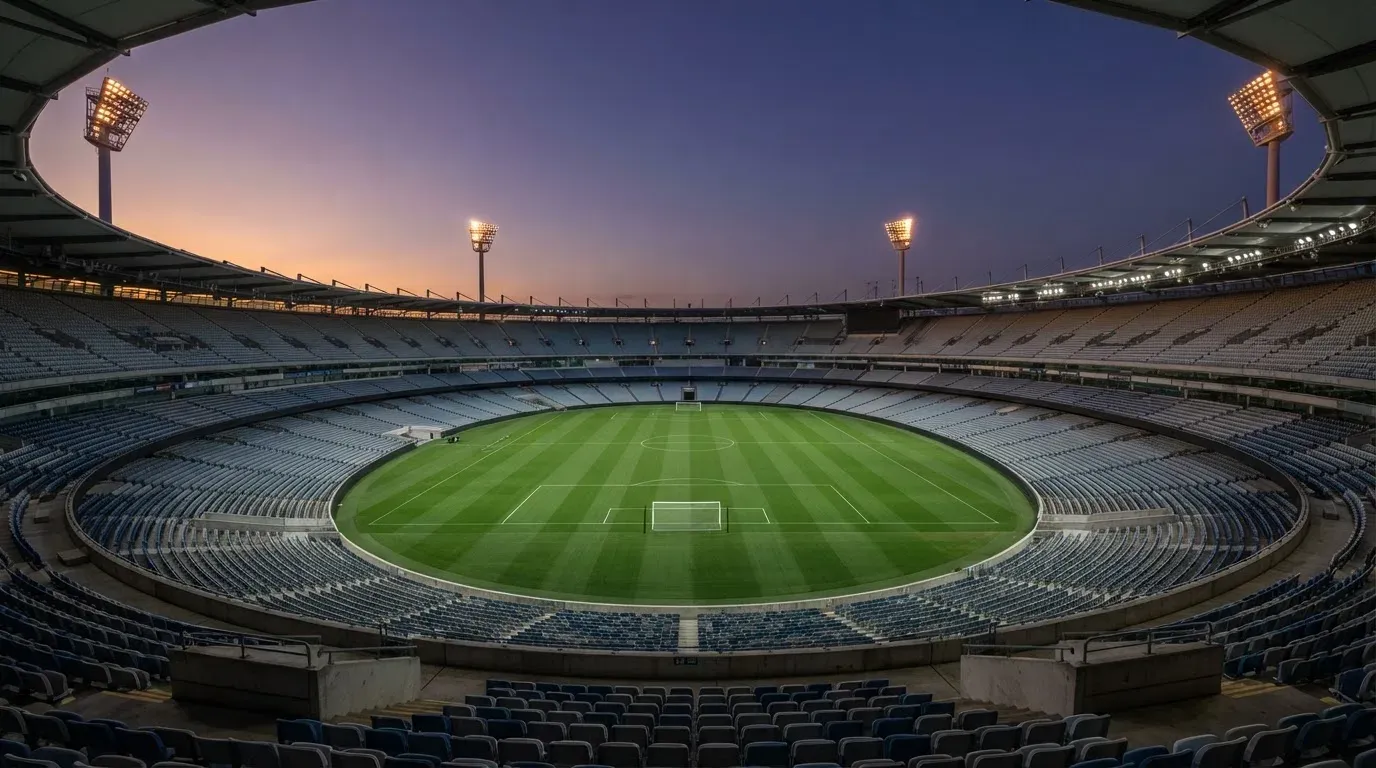 An empty football stadium with floodlight masts at dusk